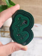 Load image into Gallery viewer, Malachite, with its striking green bands, is a powerful stone of protection and spiritual growth. It absorbs negativity and enhances your psychic abilities, making it an essential tool for manifesting your deepest desires
